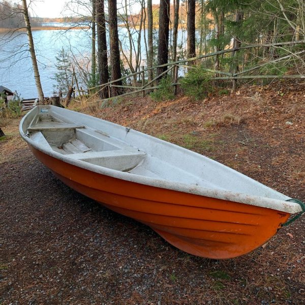 An orange and white boat sitting on the ground.